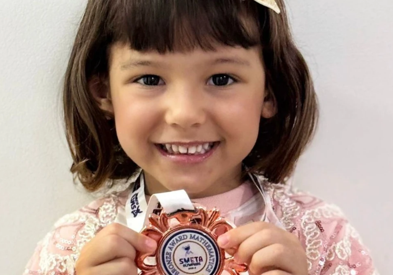 Com medalha no peito, a pequena estudante brasileira torna-se um dos destaques mais jovens da história da competição. (Foto: Reprodução/Redes Sociais)